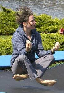 Cheryl sitting in meditation pose bouncing on trampoline