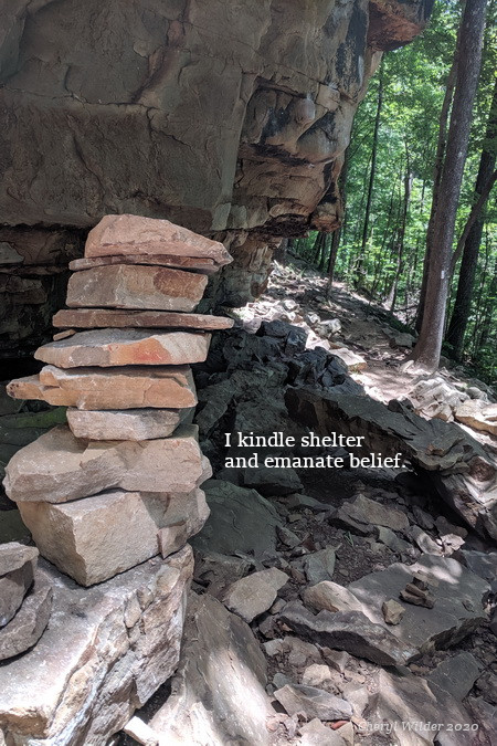 large flat rocks stacked on top of each other next to rock cliff.