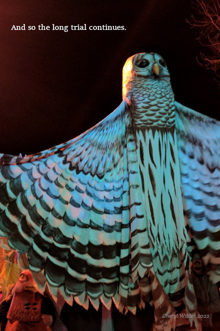 twenty-foot tall white owl puppet with arms outstretched in a parade at night